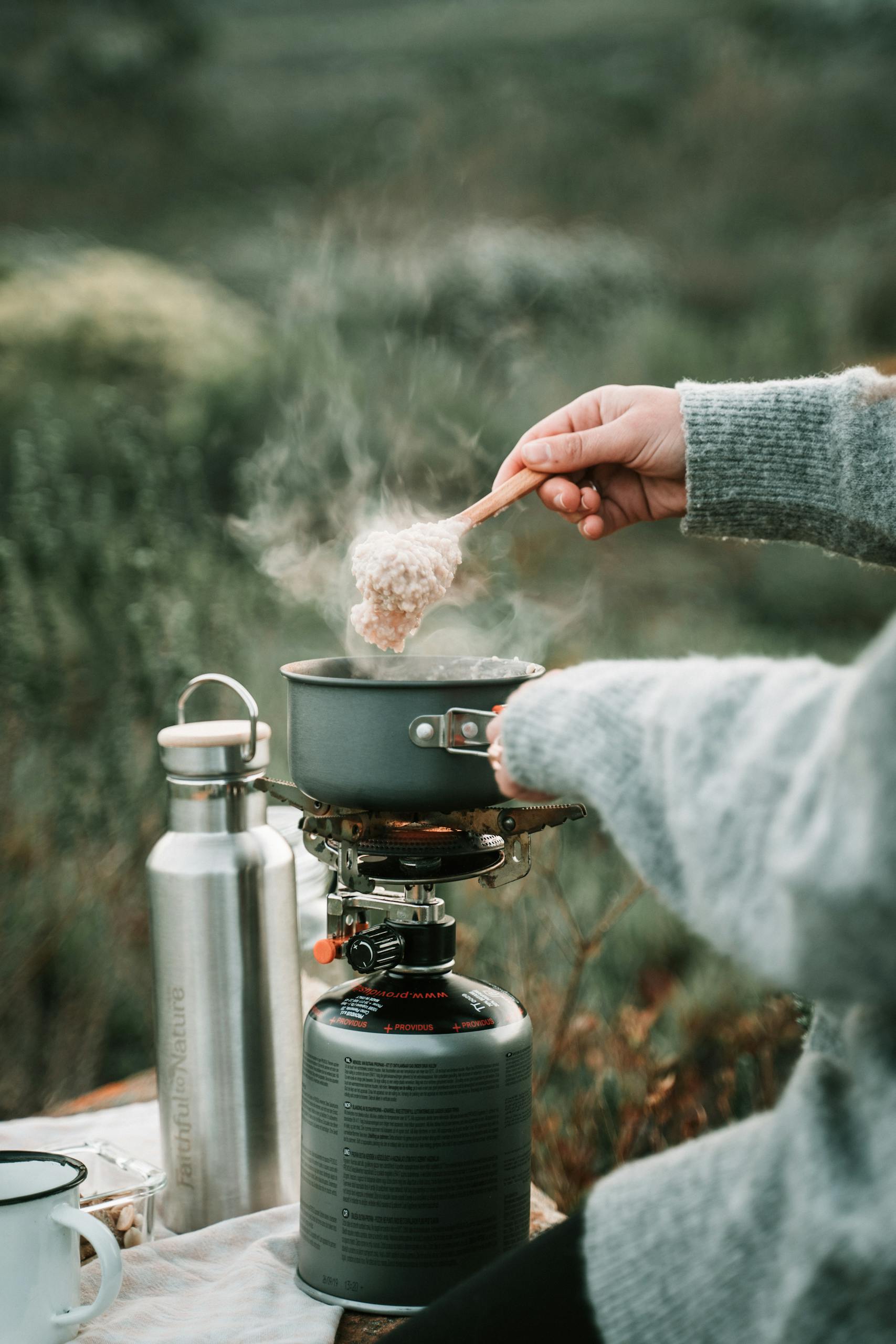 A cozy outdoor camping scene with steaming oatmeal on a portable stove, perfect for breakfast.