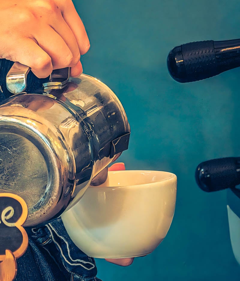 pouring milk into a coffee
