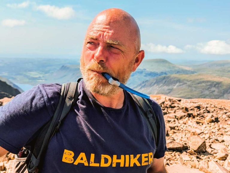 Paul Steele drinking from the tube of a water bladder on a mountain