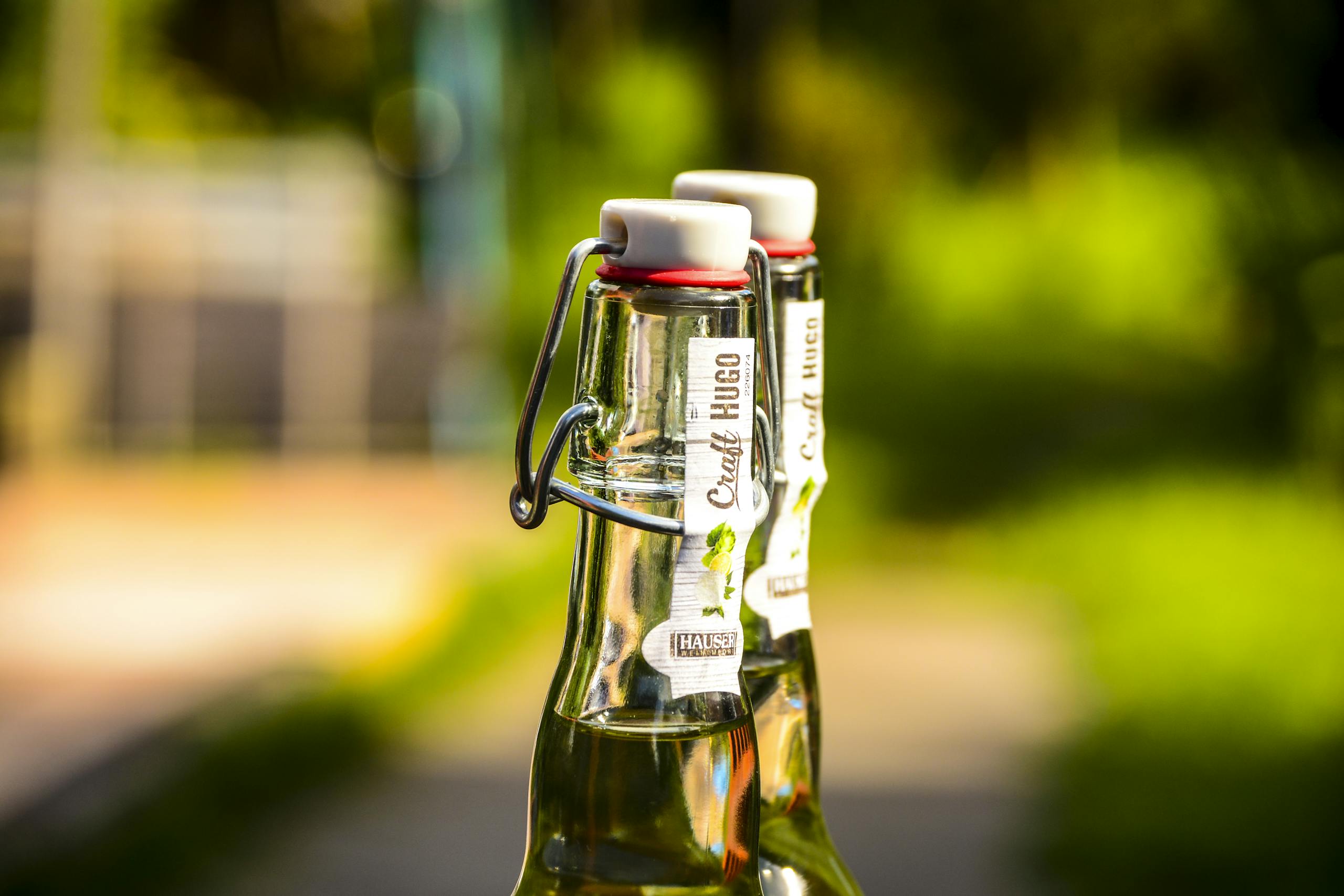 Glass bottles of cocktail with flip-tops in bright outdoor setting.