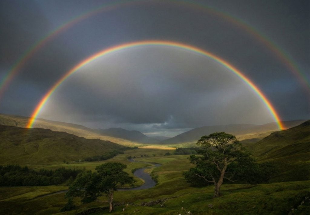 a full double rainbow against a dark, moody sky
