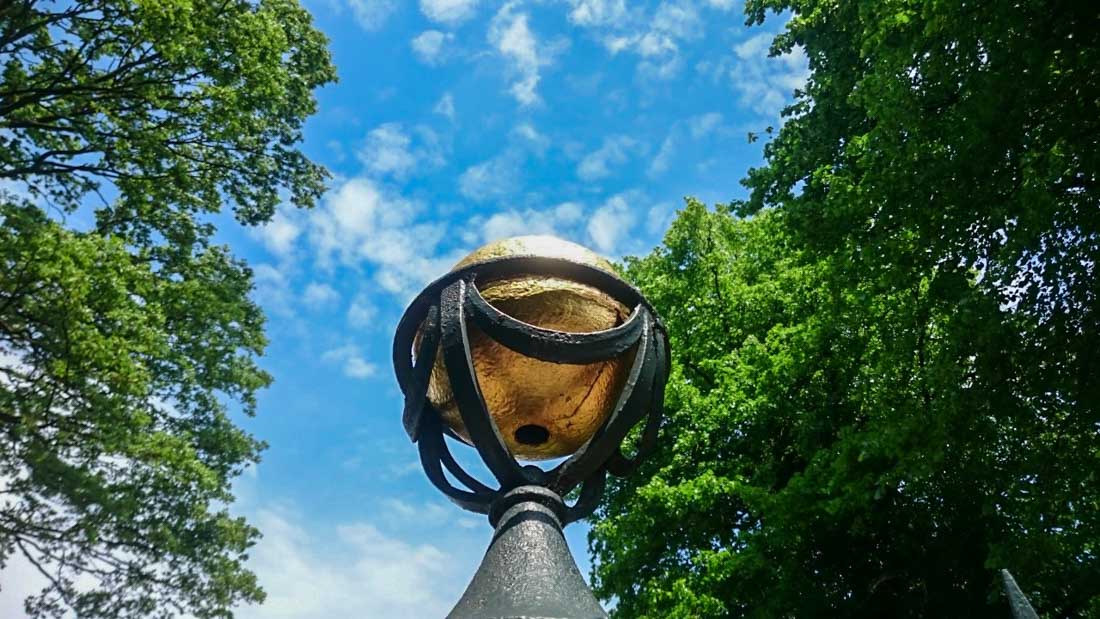 a gold ball garden ornament on a black pole